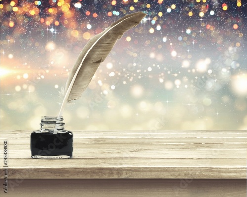 Feather quill pen and glass inkwell isolated on a white photo