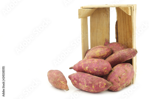 freshly harvested sweet potatoes in a wooden crate on a white background photo