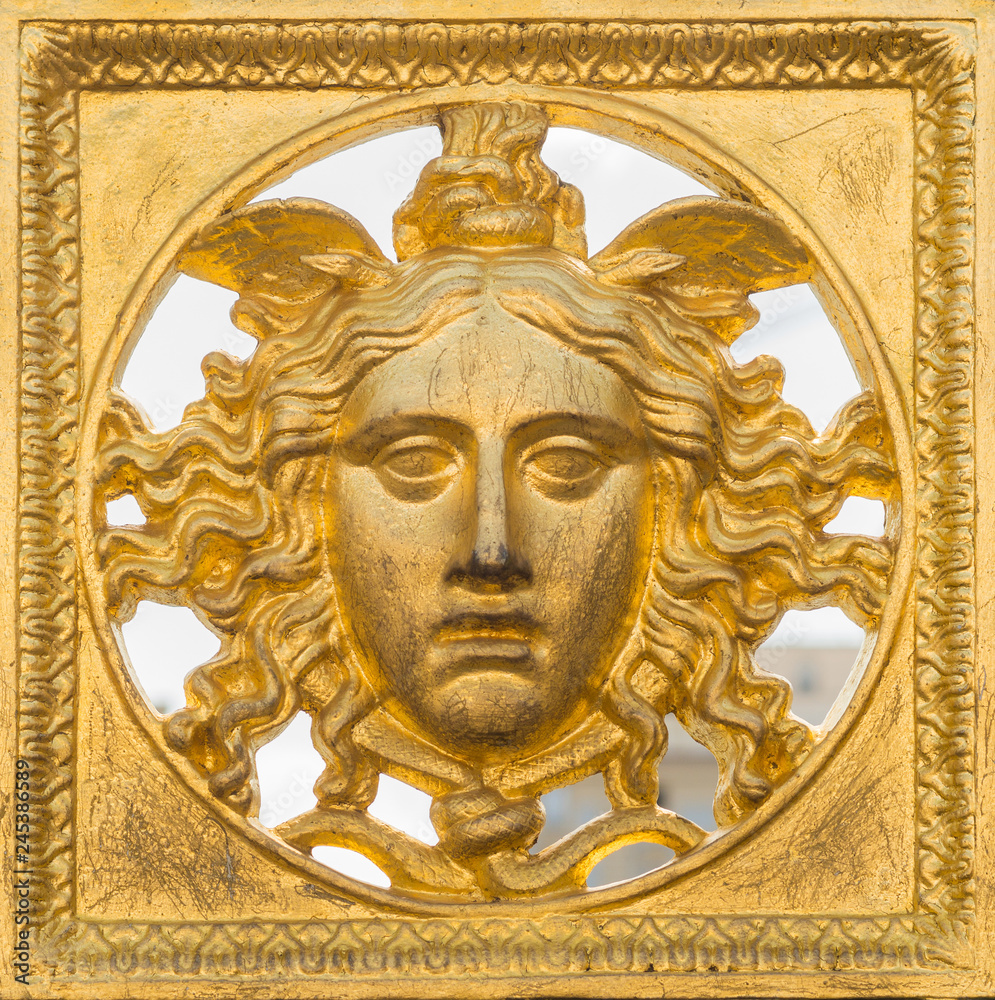 Ancient baroque golden mask on a fence at Palazzo Reale, Turin