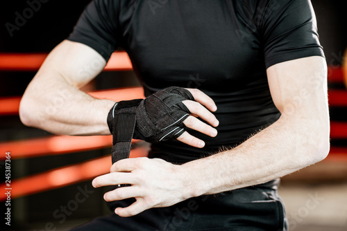 Man winding bandage on the wrists, preparring for boxing. Close-up view with no face