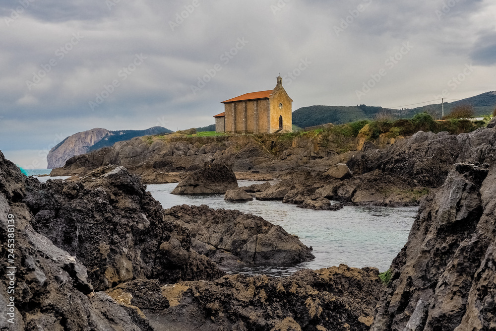 Small church of Santa Catalina on the coast of Mundaca village in Biscay during a cloudy day