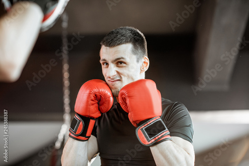 Athletic man fighting during the training with boxing trainer on the boxing ring at the gym