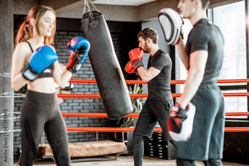 Young woman training to box with personal coach on the boxing ring at the gym