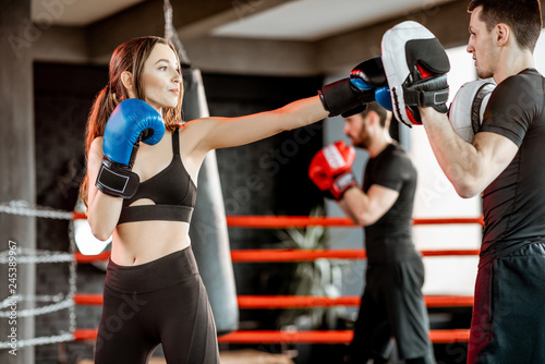 Young woman training to box with personal coach on the boxing ring at the gym © rh2010