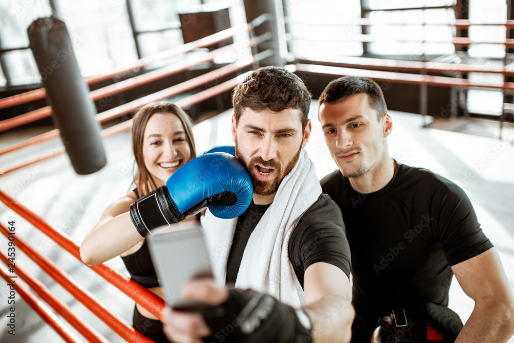 Friends making selfie portrait, having fun together during the sports break after the training on the boxing ring at the gym Friends making selfie portrait, having fun together during the sports break after the training on the boxing ring at the gym