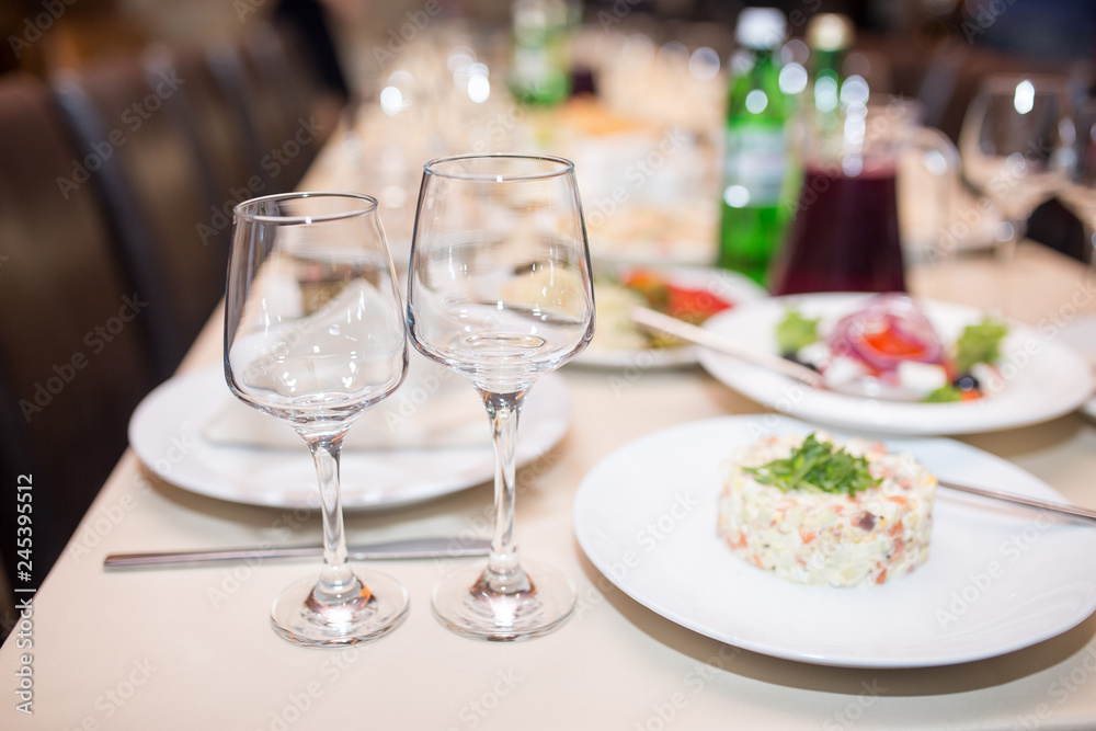 dinner set arranged on a table with vintage cream lace tablecloth and napkins, elegant porcelain dishes, silverware and crystal glassware