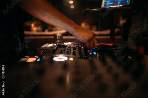 Close up of DJ's hand playing music at turntable on a party festival - Portrait of DJ mixer audio in a beach club above the crowd dancing and having fun - Party, summer, music and people concept