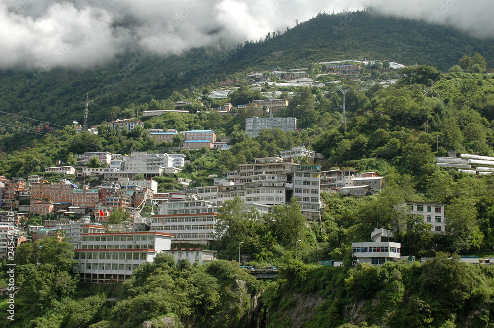 City on the slope of a green hill on the border between China and Nepal