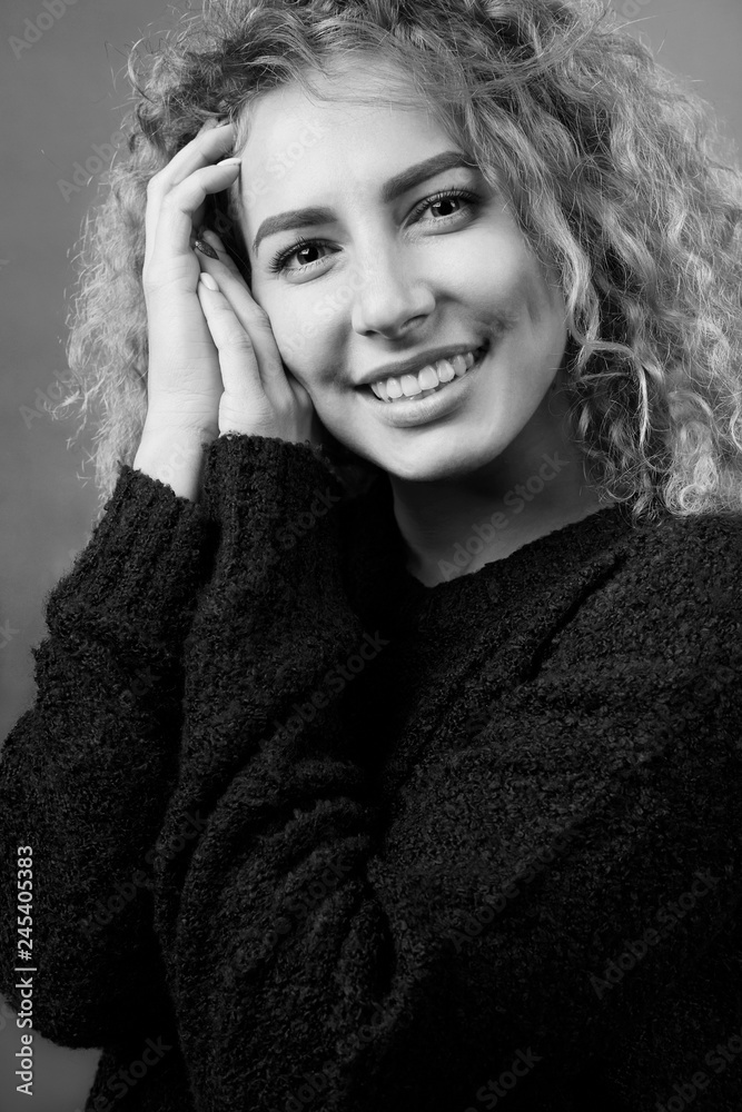 Monochrome portrait of attractive smiling cheerful curly girl dressed in black sweater. Monochrome portrait of attractive smiling cheerful curly girl dressed in black sweater.