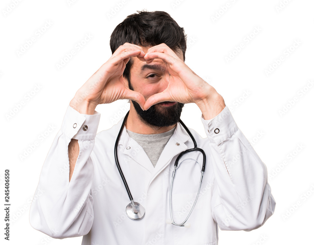 Young doctor making a heart with his hands on white background