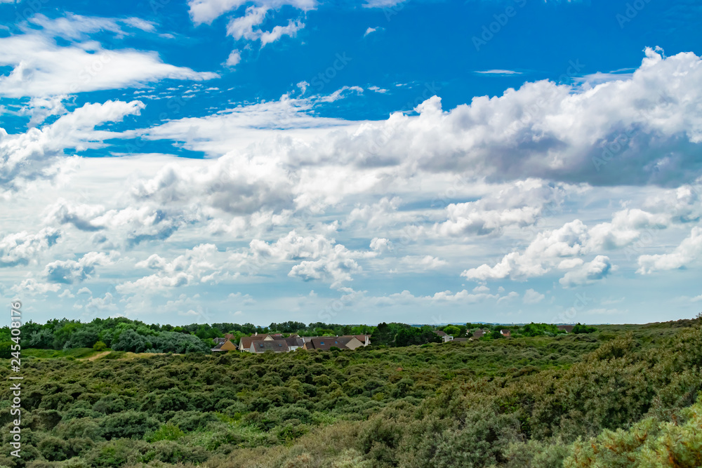View of the houses of a small town amidst beautiful coastal vegetation and blue sky with clouds in the north of france.