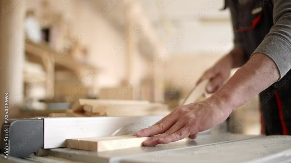 Hands of unrecognizable skilled furniture maker cutting wooden planks with electric circular saw Hands of unrecognizable skilled furniture maker cutting wooden planks with electric circular saw