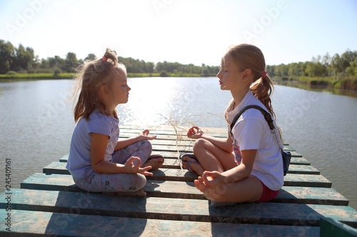 girls are meditating on the pier at the lake in the morning