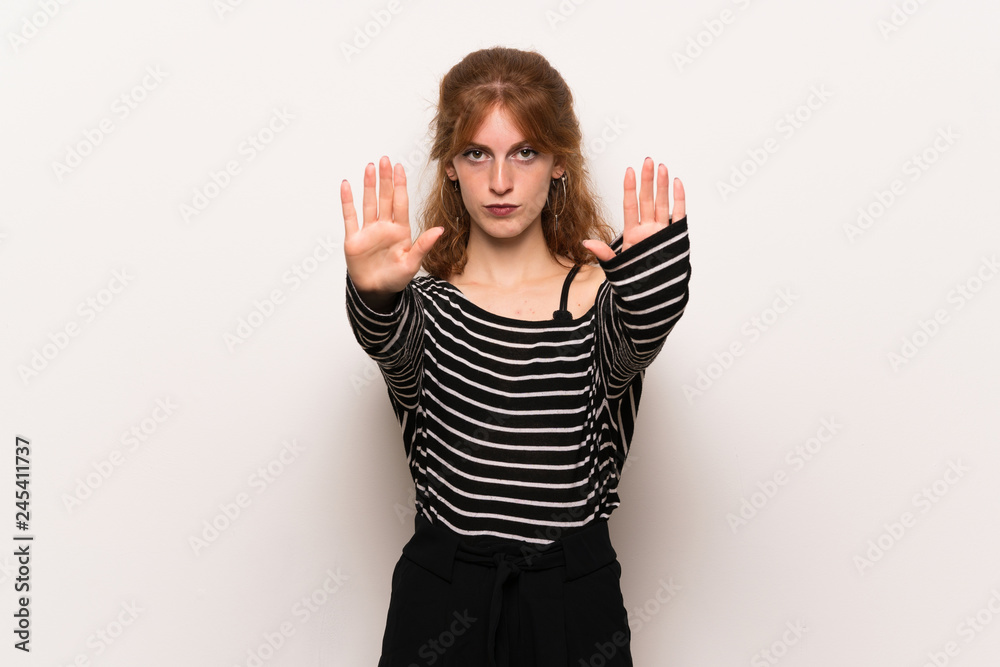 Young redhead woman over white wall making stop gesture for disappointed with an opinion Young redhead woman over white wall making stop gesture for disappointed with an opinion