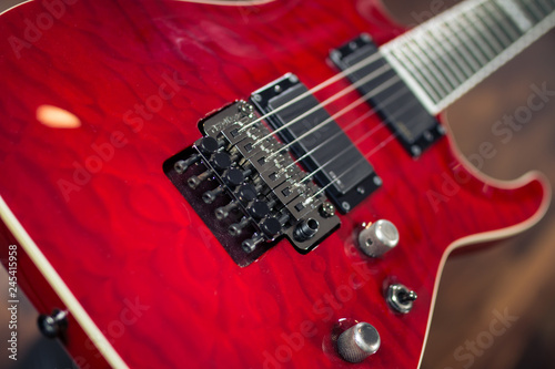 Electric guitar, red colour close up with wooden soft background
