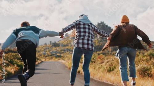 young multi ethnic friends longboarding together holding hands riding skateboard cruising downhill on countryside road having fun enjoying relaxed summer vacation photo