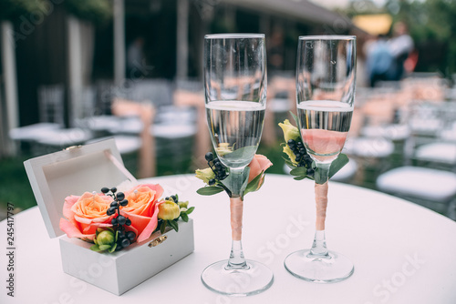 Two wedding glasses and bridal bouquet on stone in summer garden