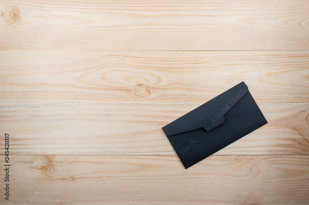 Black single envelope on a natural wooden table. top view, copy space Black single envelope on a natural wooden table. top view, copy space
