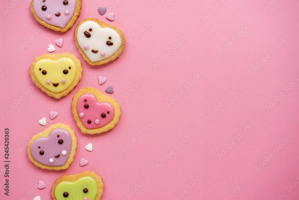 Heart shaped sugar cookies decorated with pastel royal icing on pink background