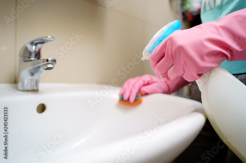 Fototapeta Naklejka Na Ścianę i Meble -  Image of hands in pink rubber gloves washing sink in bath