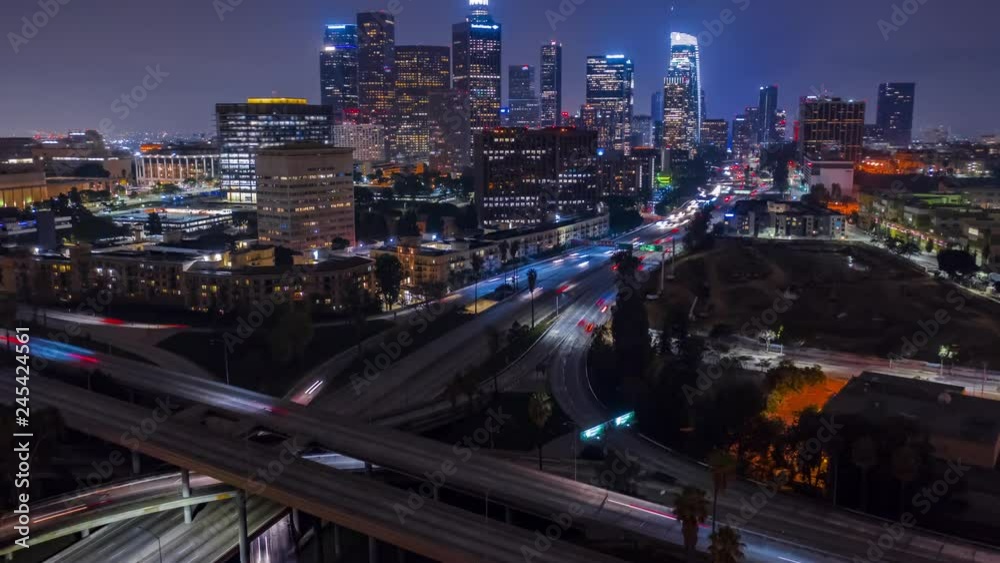 Aerial evening timelapse in motion (hyperlapse) facing downtown Los Angeles at night with traffic on a busy freeway below.