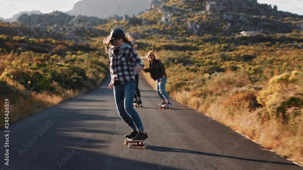 happy multi ethnic friends longboarding together riding skateboard cruising on countryside road having fun hanging out enjoying relaxed summer vacation