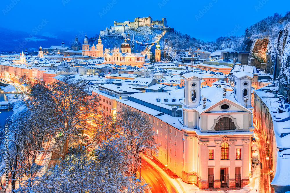Naklejka premium Salzburg, Austria: Zimowy widok na historyczne miasto Salzburg ze słynnym Festung Hohensalzburg i rzeką Salzach oświetlone w pięknym zmierzchu podczas malowniczych świąt Bożego Narodzenia w zimowym