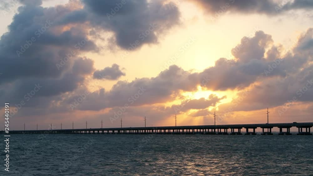 Dramatic orange cloudy sunset at seascape of Bahia Honda State Park in Florida Keys with old seven mile railroad bridge, overseas highway at gulf of mexico, clouds moving Dramatic orange cloudy sunset at seascape of Bahia Honda State Park in Florida Keys with old seven mile railroad bridge, overseas highway at gulf of mexico, clouds moving