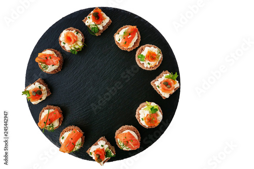 Smoked salmon canapes with cheese cream and dill served on black round slate platter