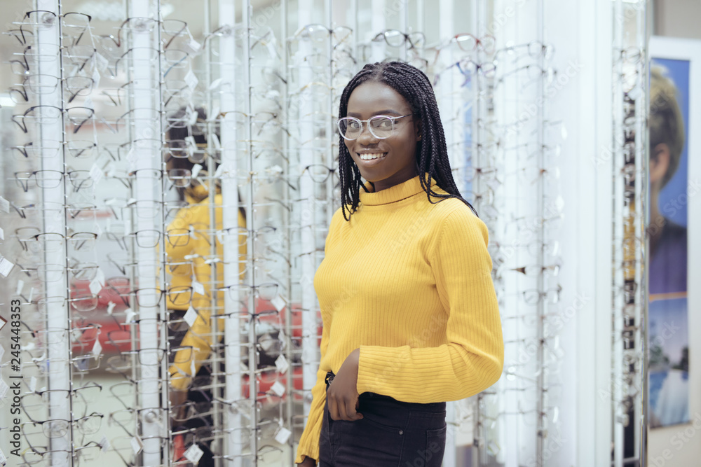 Young pretty african woman choosing eyeglasses frames in Optician's shop. Young pretty african woman choosing eyeglasses frames in Optician's shop.