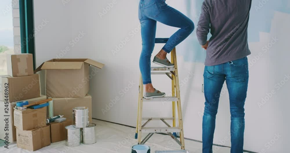 Cute couple painting wall in new home and kissing, happy new homeowners, home painting