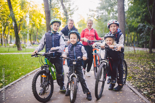Theme family sports vacation in park in nature. big friendly Caucasian family of six people mountain bike riding in forest. Children brothers and sister stand on the background of parents in a row
