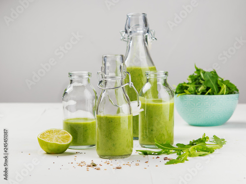 Fresh made healthy green smoothie served in bottles on white background. Fruits and vegetables and seeds ingredients around. Close with copy space. Lifestyle.