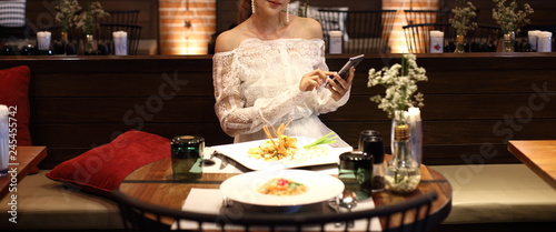 Woman white lace dress have dinner in restaurant with low light candle waiting for lover to join celebrate anniversary night together but come so late and feel bad, copy space photo