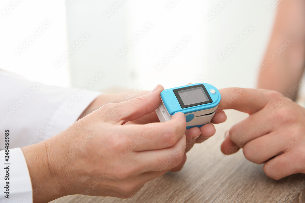 Doctor checking man's pulse with medical device in hospital, closeup Doctor checking man's pulse with medical device in hospital, closeup