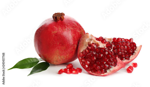 Ripe pomegranates with leaves on white background