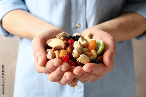 Young woman holding handful of different dried fruits and nuts, closeup