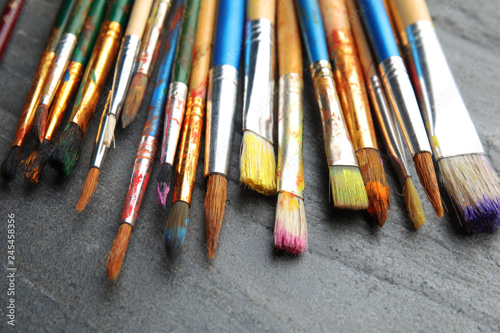 Fototapeta premium Different paint brushes on grey table, closeup