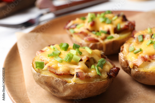 Plate of baked potatoes with cheese and bacon on table, closeup