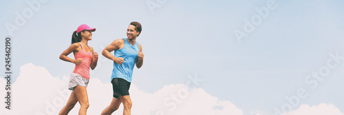 Healthy people fit active lifestyle couple running on sky background panoramic banner. Happy friends exercising together -training buddy.