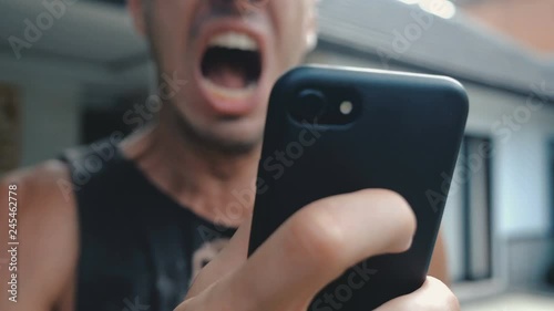 Angry Man Using Smartphone. Man is angry with the message that he read in the smartphone. Angry man uses smartphone. photo