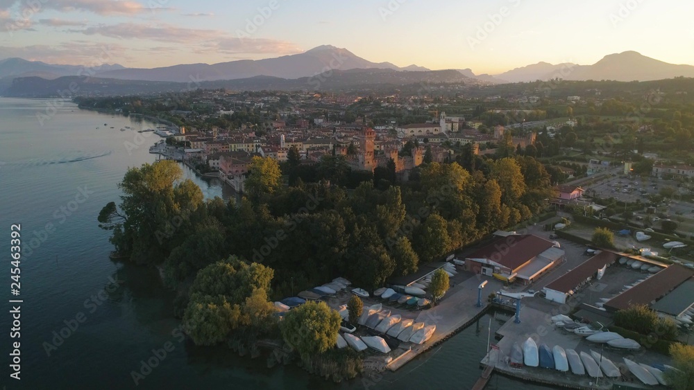Italian castle at sunrise, C4k aerial, tracking, drone shot, of Lazise fortress, at lago di Garda, on a sunny, summer morning dawn, in Verona, Italy