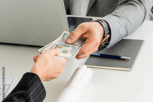 Businessman hand sending money to another business person. Transaction, payment, salary and banking concept.
