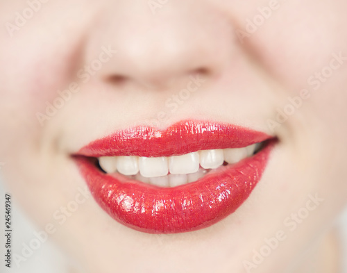 White teeth and red lipstick on the lips. Beautiful mouth. Charming woman's smile. Dental care and Stomatology concept. Girl is very happy.