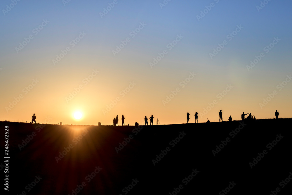 Silhouettes of hikers with backpacks enjoying sunset view from top of a mountain