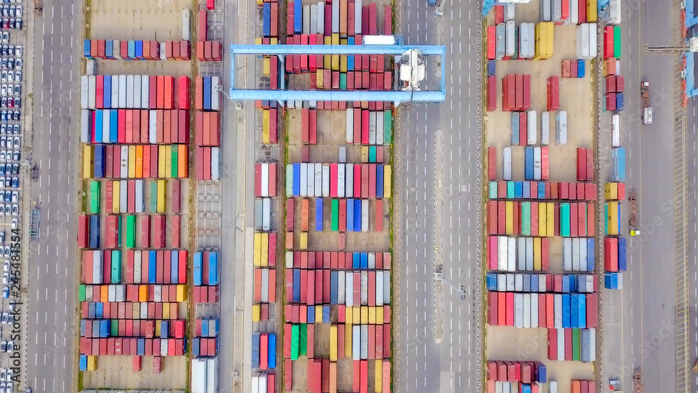 Transtainer yard - Various brands and colours of Shipping containers stacked by Transtainers (Mobile gantry cranes) off of service trucks - Top down aerial image Transtainer yard - Various brands and colours of Shipping containers stacked by Transtainers (Mobile gantry cranes) off of service trucks - Top down aerial image