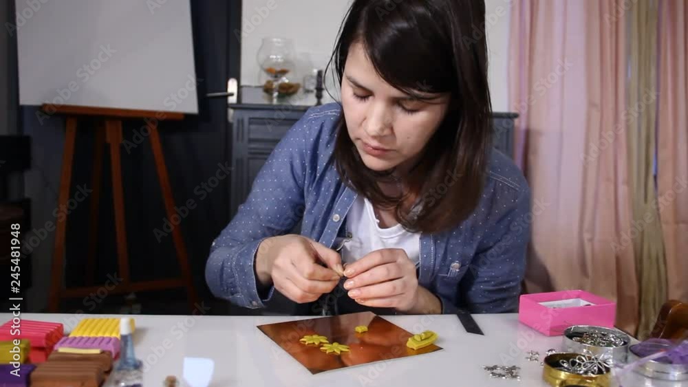 Woman creating hand made jewelry from polymer clay in her studio.