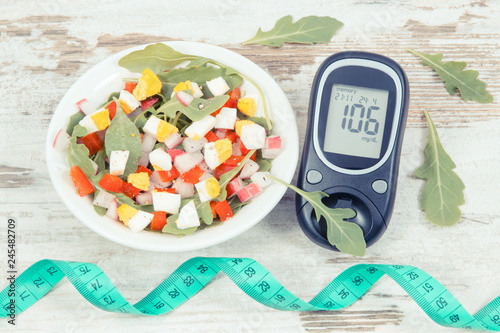 Glucometer with result of sugar level, centimeter and salad with eggs and vegetables, diabetes and alimming concept photo