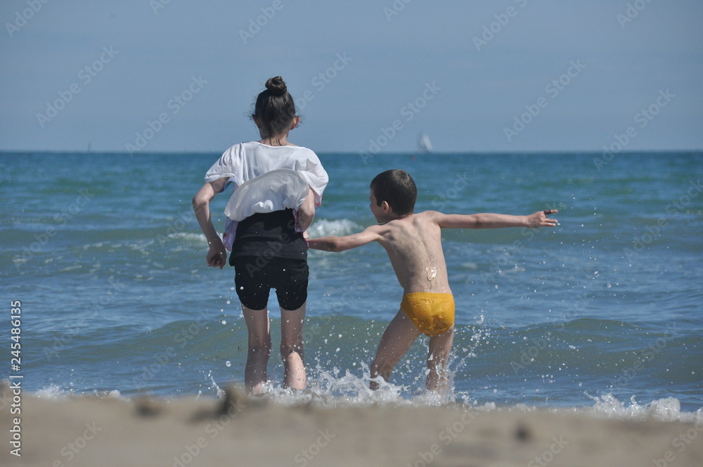 Children, siblings playing on the sea shore. They jumping in the waves. Children, siblings playing on the sea shore. They jumping in the waves.
