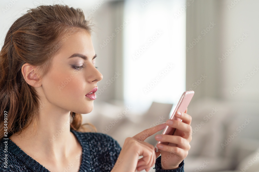 Attractive young woman looking at her smart phone at home Attractive young woman looking at her smart phone at home